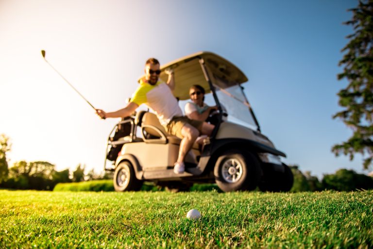 Golf ball on grass near a golf cart showing the risk of stray golf balls near solar homes.